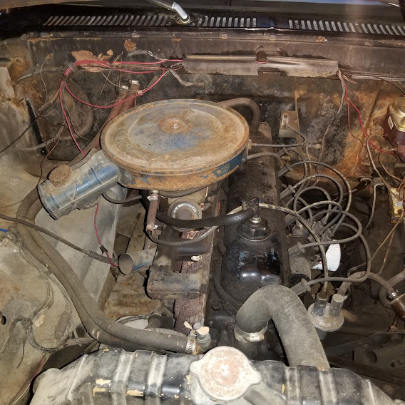 The engine compartment, showing rust and tangled wires.